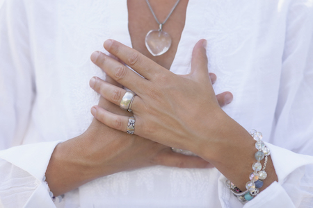 Wellbeing coach practicing mindful acceptance meditation over heart chakra