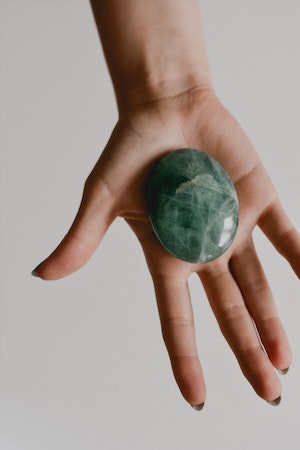 A hand holding a green crystal